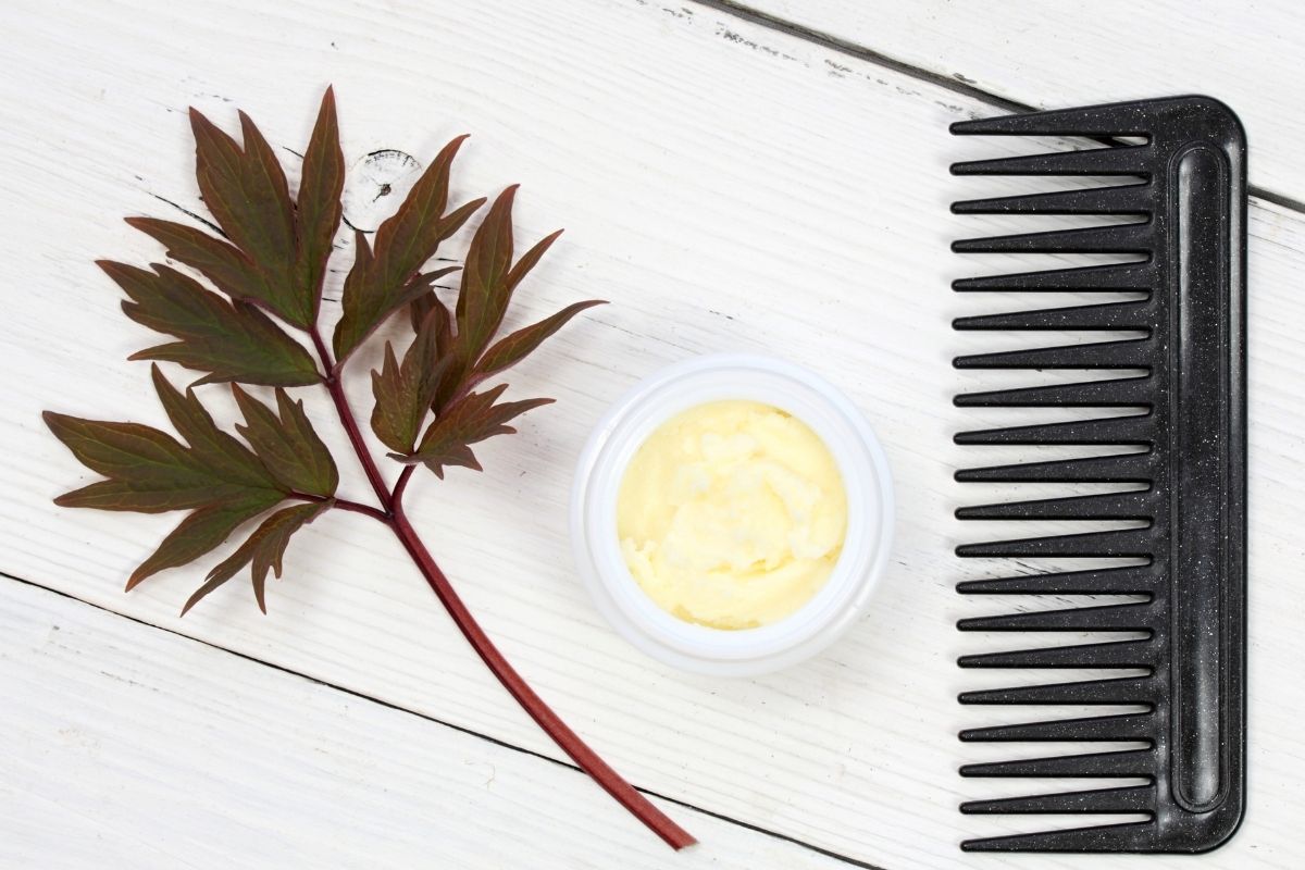 A comb next to a cup of shea butter.