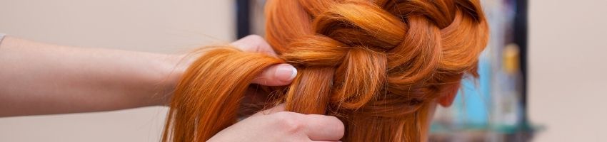 A close up of a person getting their hair braided.