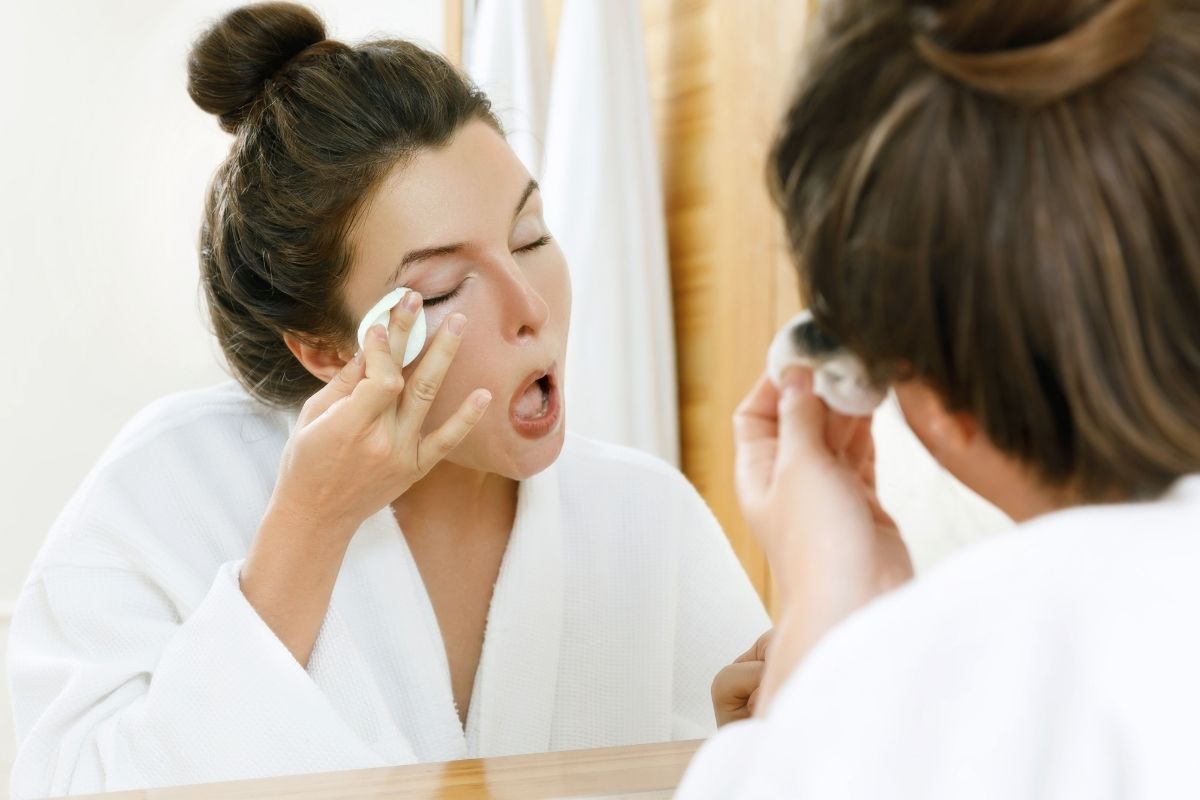 A woman wiping her eye makeup while wondering how to remove eyebrow tint.