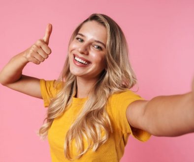 a woman with the right thumbs up taking a selfie in a pink wall