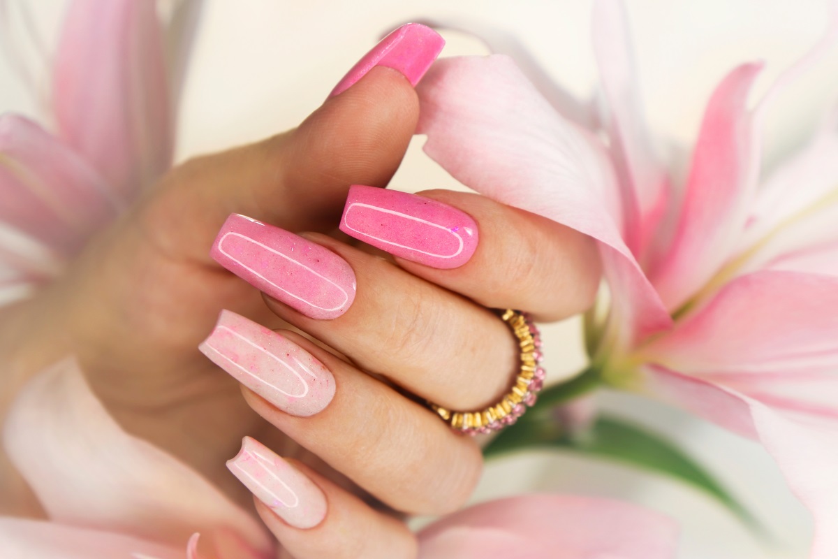 A woman is touching the flowers using her sculpted nails. 