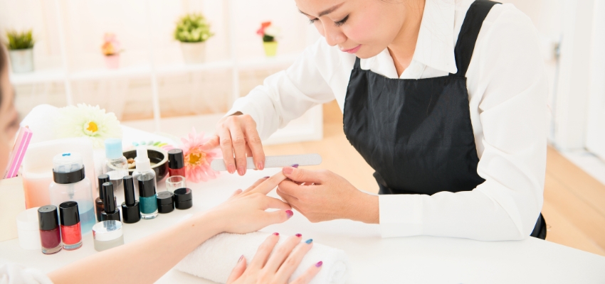 Professional nail technician using nail art tools during a client manicure session