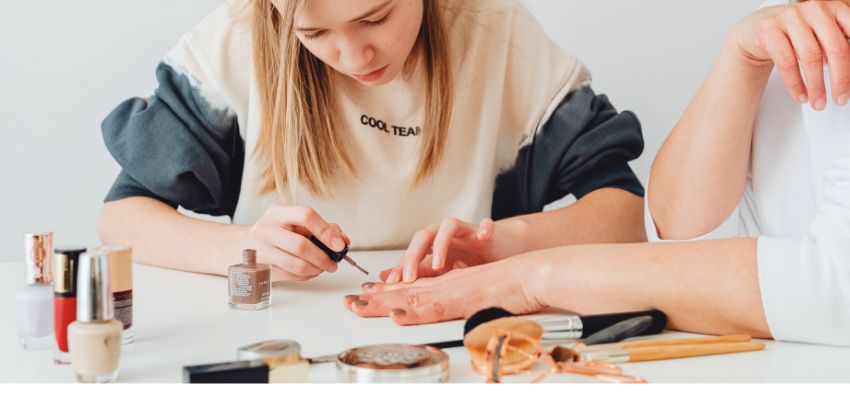 Person applying polish during a manicure while exploring what can i use instead of nail glue.