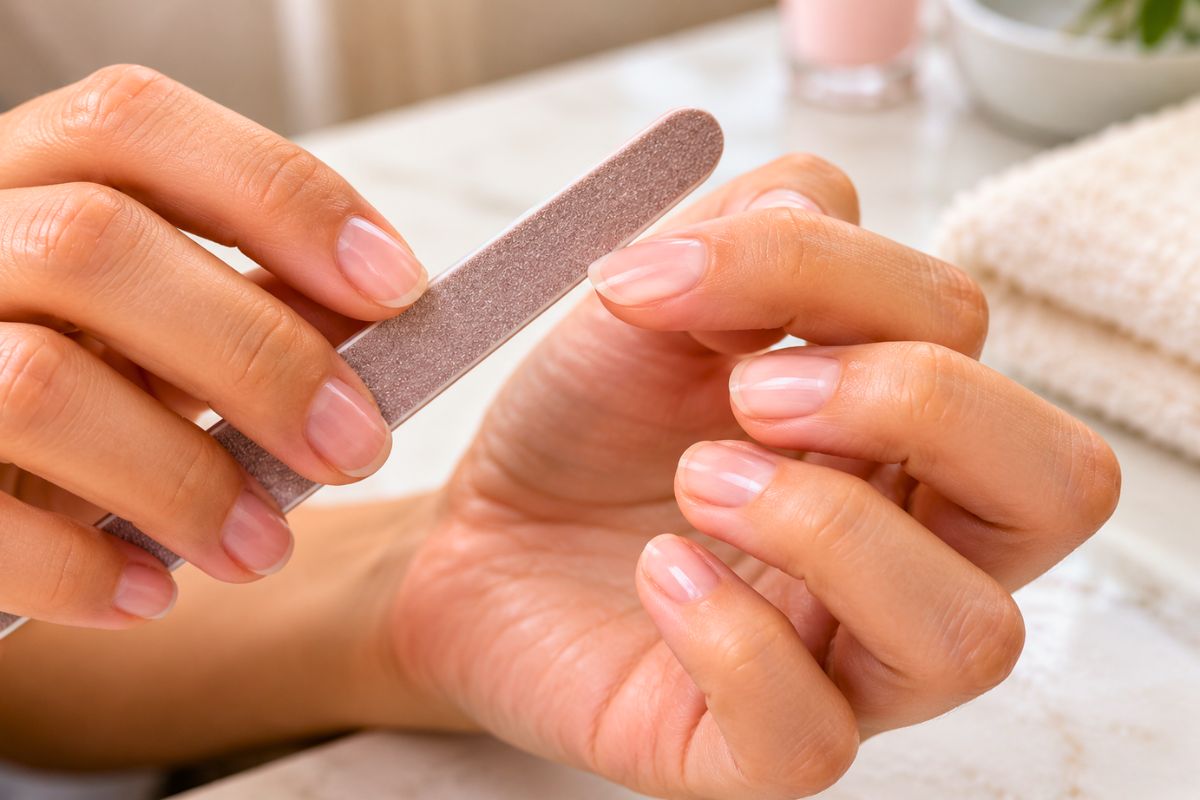 Hands carefully filing nails with a buffer for a smooth, polished finish.